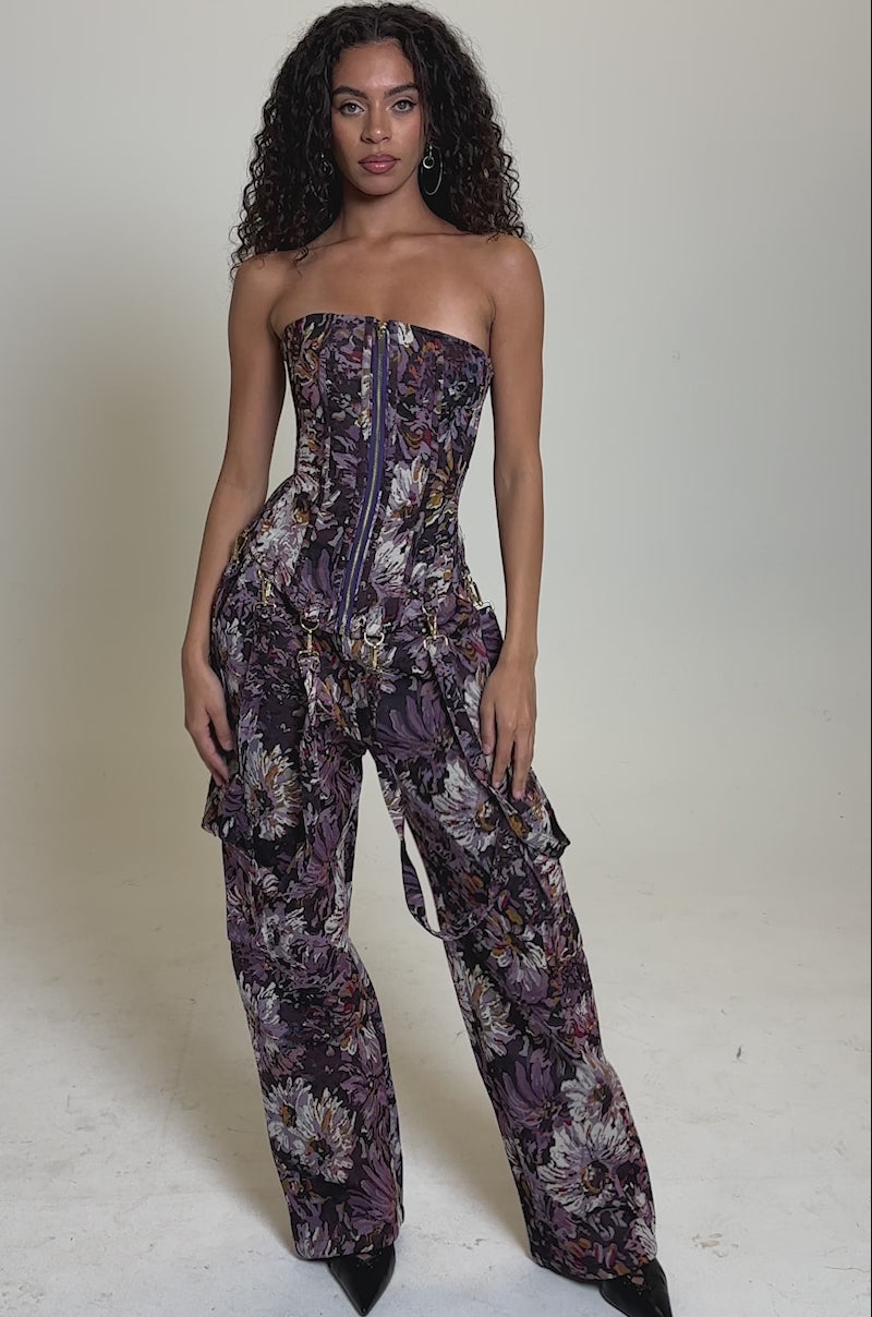 Video of woman modeling ABOVE THE MIDDLE FLORAL TROUSER—a high-rise, wide-leg silhouette in purple, pink, and white—with a matching strapless corset top and black pointed shoes.