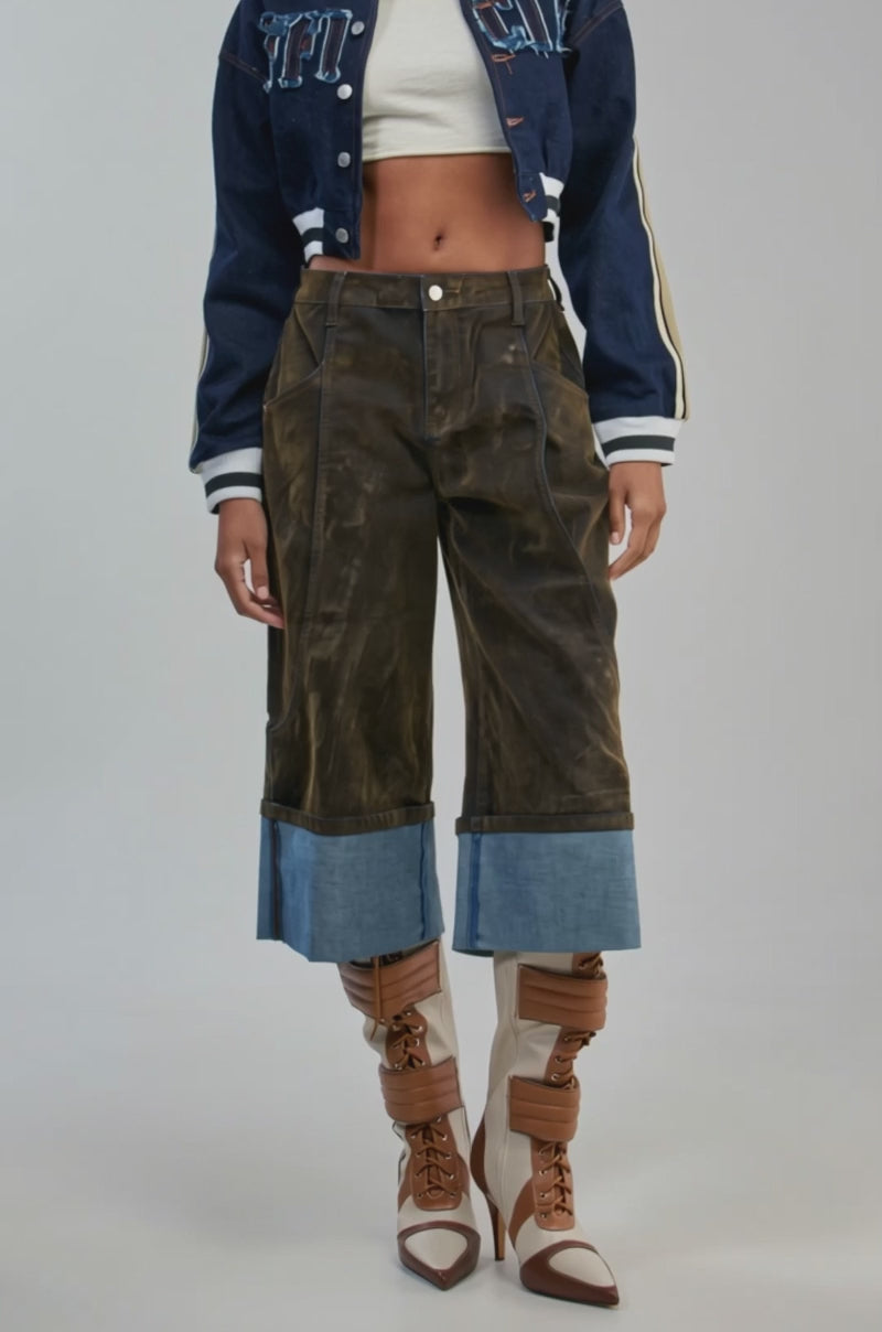 Video of a woman modeling the OFFICIAL DENIM BOMBER, a dark wash varsity-style jacket with frayed lettering.