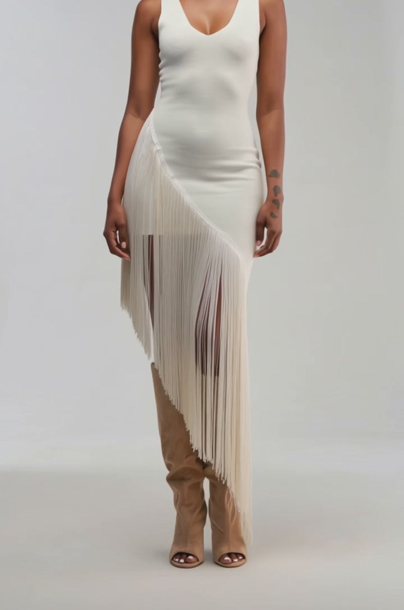 Video of a woman modeling the SHAKE IT FRINGE MIDI DRESS IN WHITE—a sleeveless, asymmetrical midi dress featuring dramatic long fringe on one side.