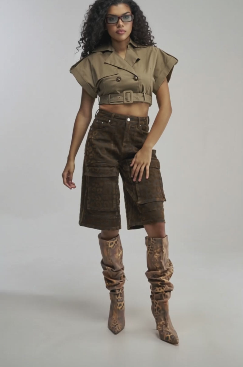 Video of woman modeling the OUT AND ABOUT CROPPED TRENCH TOP, styled with high-waisted brown patterned pants, as she stands against a plain background.