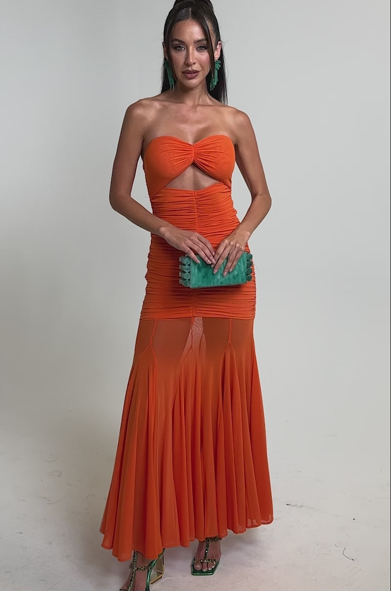 A video of a woman wearing the CABANA CHILL CINCHED MAXI DRESS, a strapless ruched orange maxi with a front cutout and sheer skirt. 