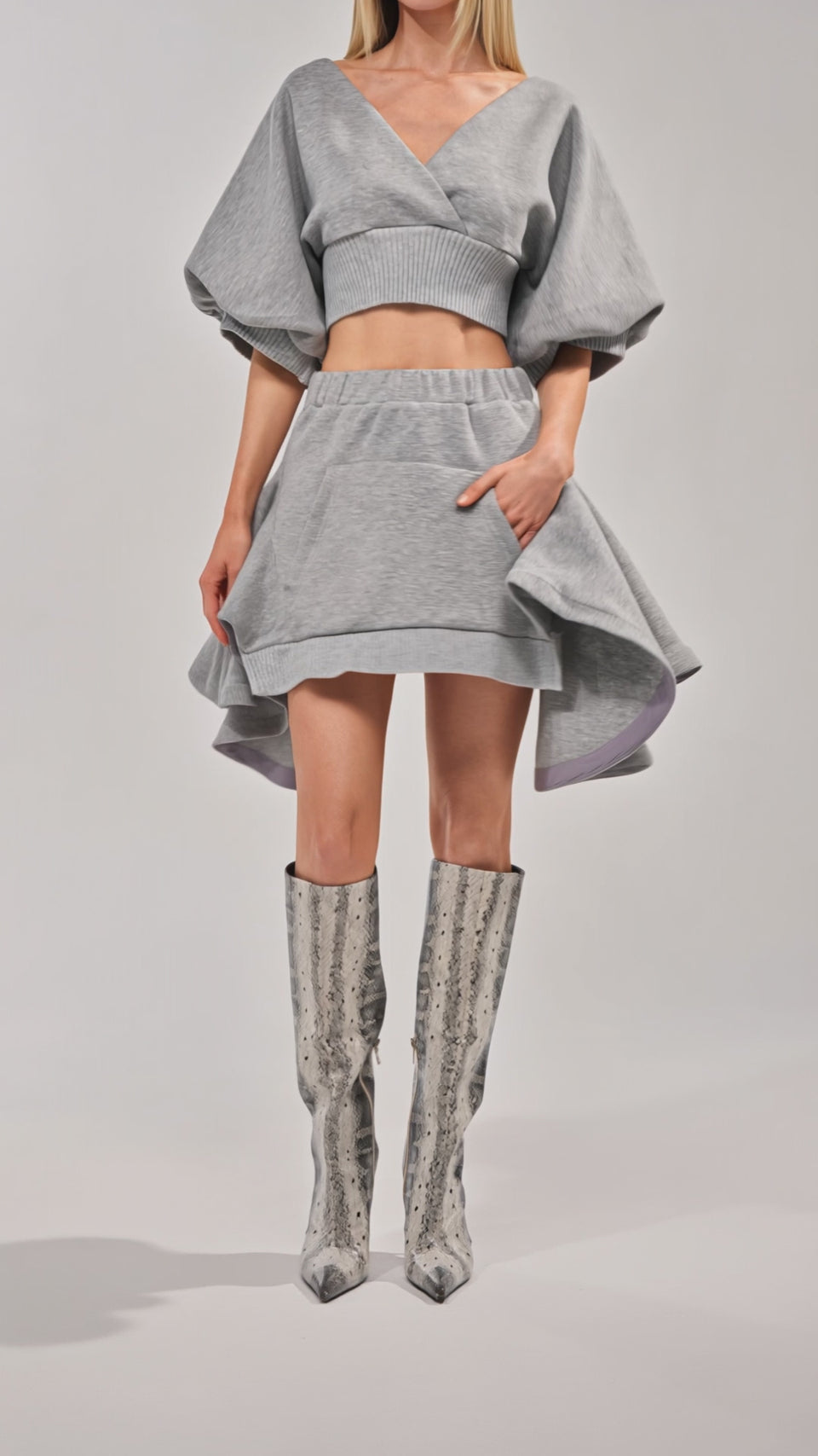 Video of woman modeling the NO WORK ALL PLAY SCUBA SKIRT in light gray, and knee-high pointed-toe snakeskin boots, all set against a plain light background.
