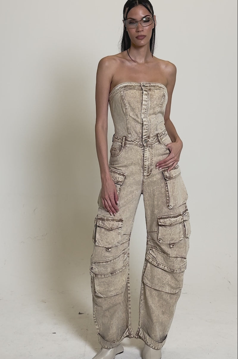 Video of woman modeling the JESSICA DENIM CARGO JUMPSUIT with multiple cargo pockets poses confidently in white pointed-toe heels against a plain background.