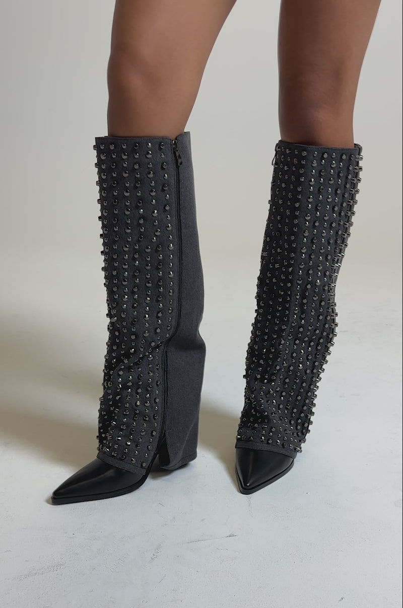A video of the AZALEA WANG AGUSTUE BLACK STUDDED WESTERN BOOT, a knee-high, dark gray denim boot with silver studs, pointed black leather toes, and chunky heels inspired by western style.