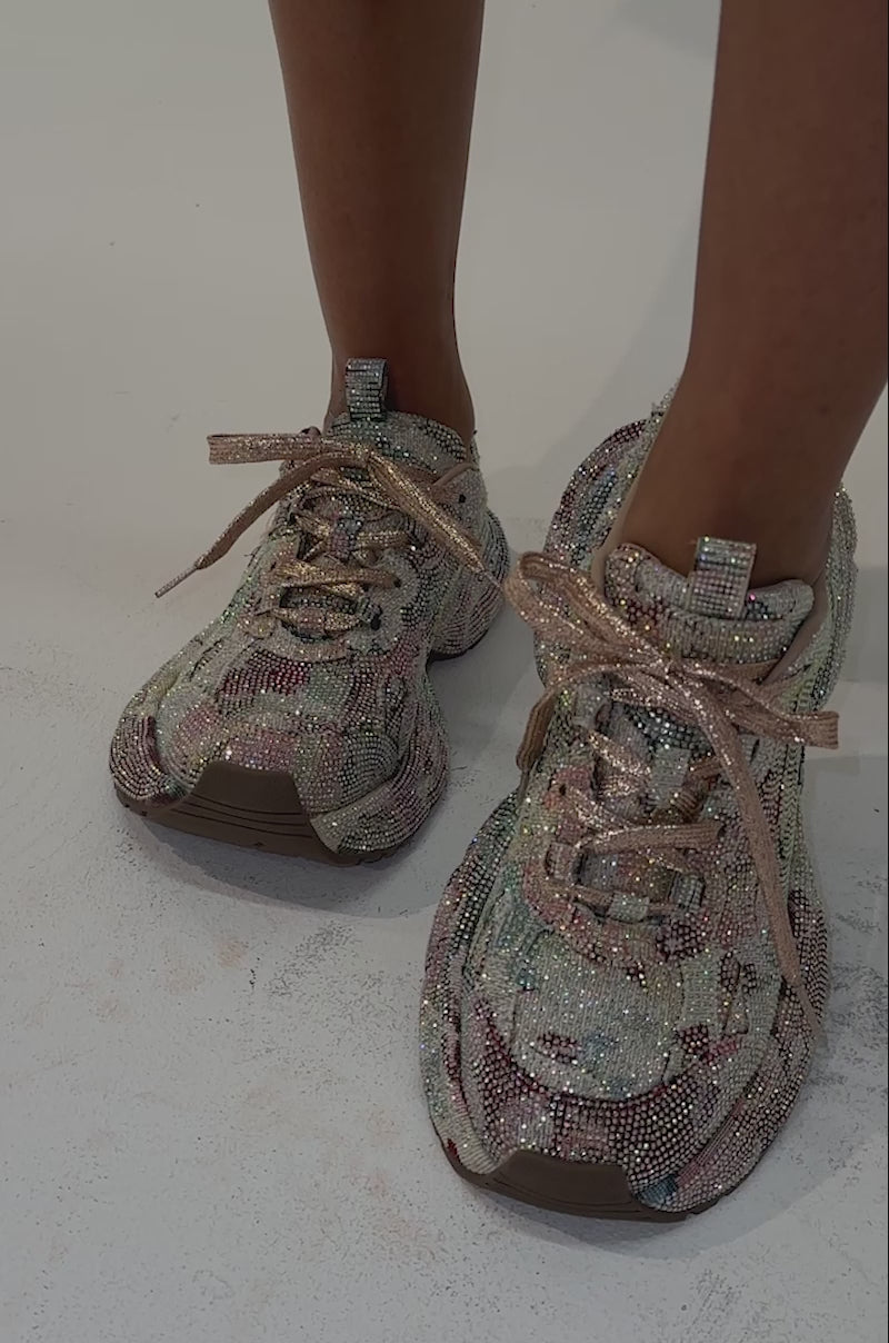 Video of a woman modeling the AKIRA GOLD MORA MULTI FLORAL RHINESTONE SNEAKER, featuring shimmering multicolored floral rhinestones and platform soles with laces. 