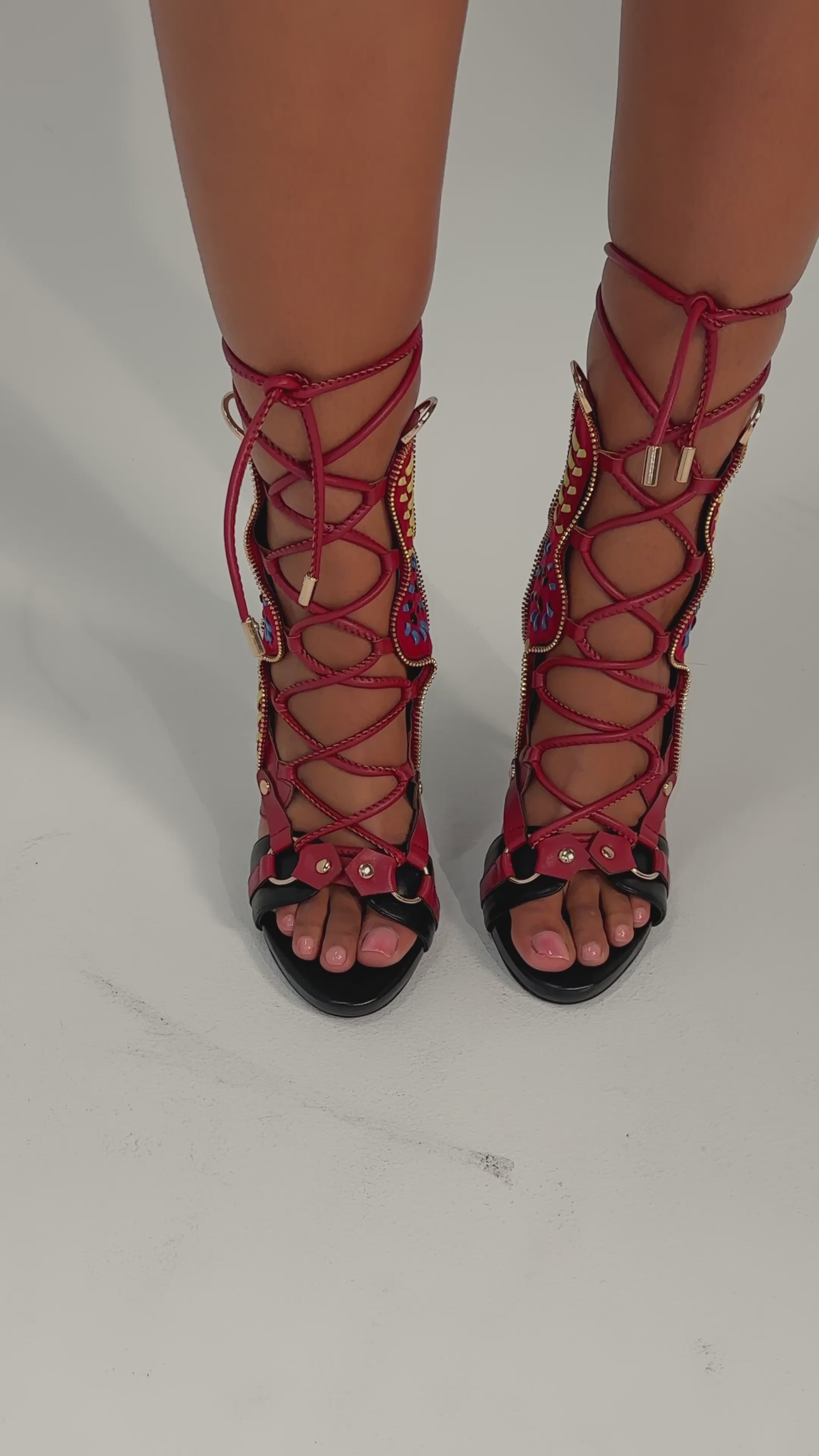 A video of a person wearing the AZALEA WANG SHAINIA BLACK MULTI SUEDE STILETTO SANDAL, which features intricate red, blue, and yellow lace-up details and a comfort cushion insole against a plain background.