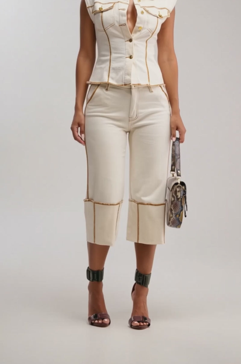 Video of woman modeling the IM ALL YOURS STRAIGHT LEG CAPRI pants, a cream short-sleeve button-up top, high-heeled ankle-strap sandals, and holding a small patterned handbag.