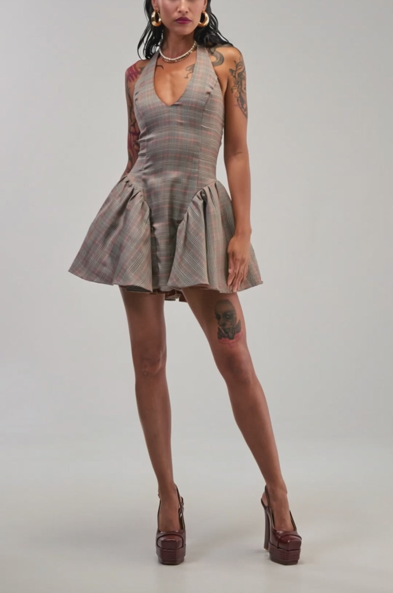Video of a woman modeling the STYLE AND GRACE MINI DRESS IN PLAID layered over a white blouse, platform boots, and carrying a brown bag. 