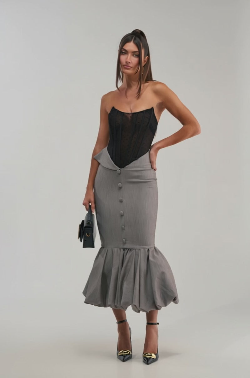 Video of woman modeling the CORPORATE BADDIE MAXI DRESS, styled with a black handbag and black ankle-strap heels.