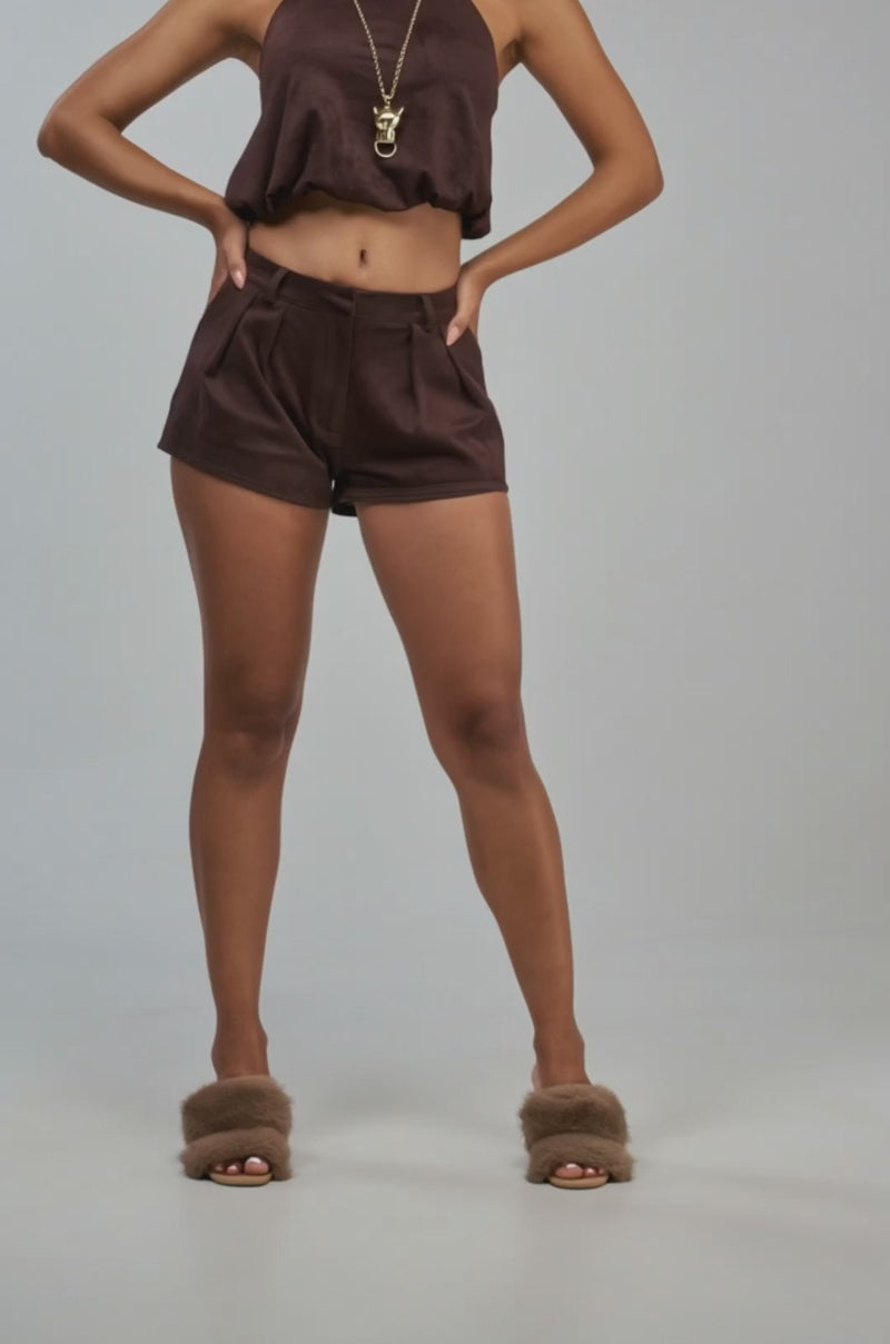 Video of a woman modeling the CALM BUT DEADLY SUEDE TOP, a brown faux suede halter styled as a backless cropped top.