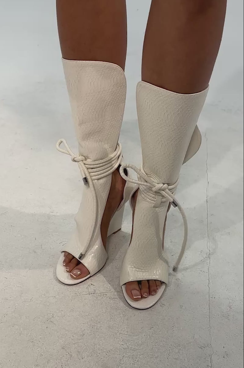 Video of woman modeling the AZALEA WANG DOUMA White Wedge Lace Up Tall Shaft Sandal against a neutral background.