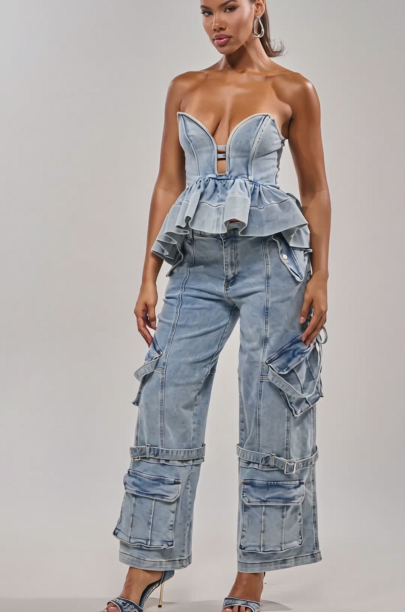 Video of woman modeling the KARA DENIM BLOUSE paired with matching high-waisted jeans featuring side ties, creating a chic festival outfit against a plain light background.
