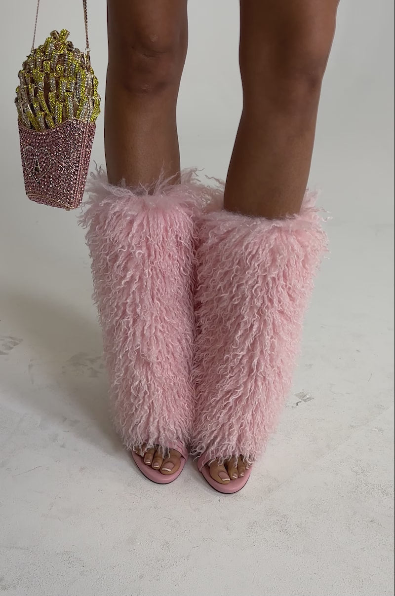 A video of a person wearing the AZALEA WANG CLOUD NINE PINK FUR OPEN TOE BOOT and a pink floral skirt, holding a french fry-shaped beaded purse. 