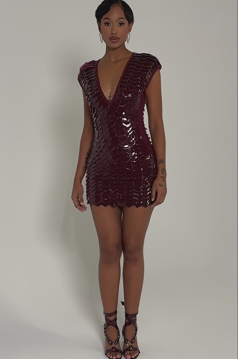 Video of woman modeling the CRAZY IN LOVE SCALE MINI DRESS, a shiny deep burgundy faux patent leather piece featuring a scale-textured pattern and deep V-neckline
