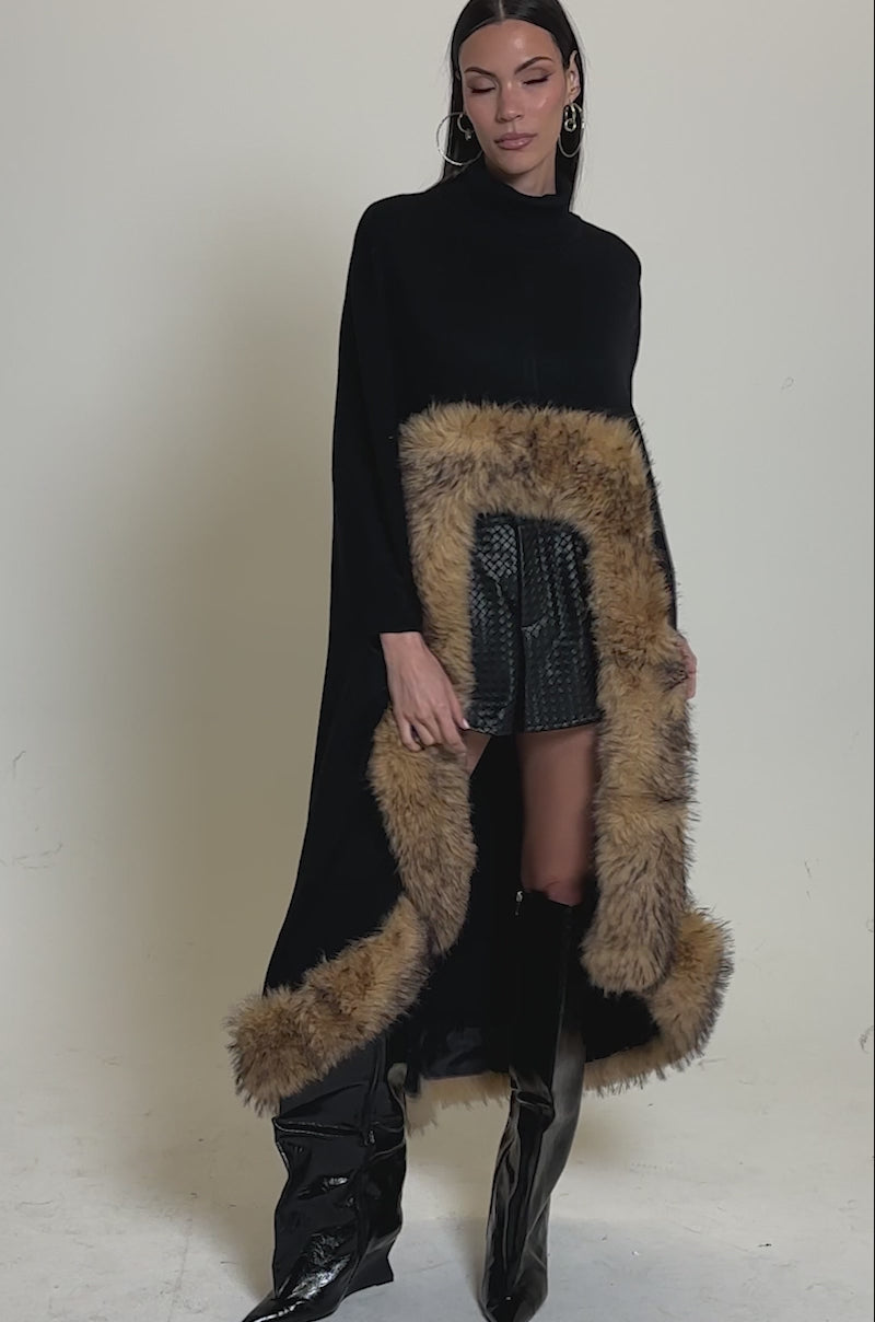 A video of a woman wearing the RICH SWEATER WITH FUR TRIM as a winter layering piece, paired with black textured shorts and shiny black knee-high boots.