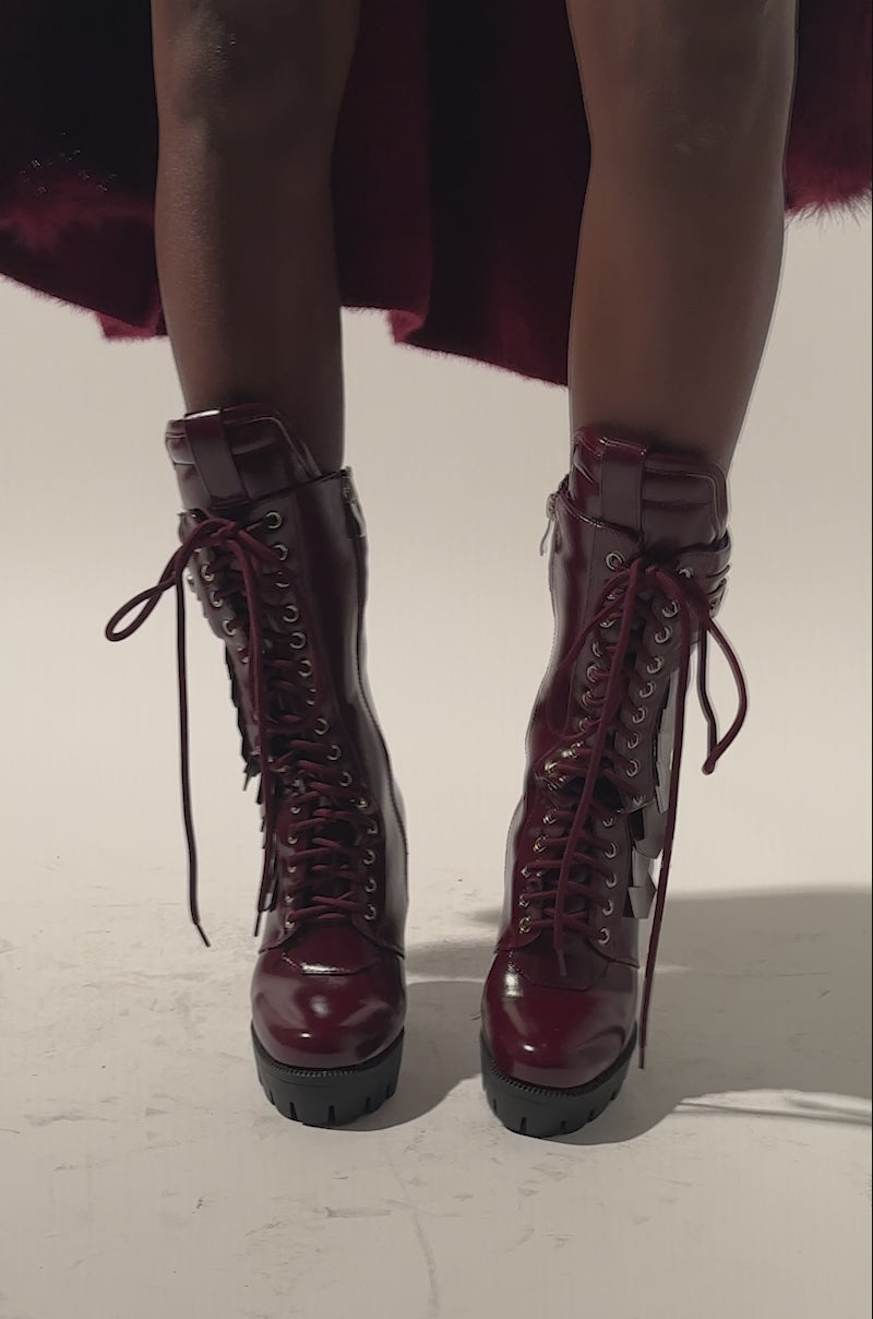 A video of a model wearing the AZALEA WANG GERNOT BURGUNDY LACE UP SCALED PLATFORM BOOTIE and a matching burgundy outfit.