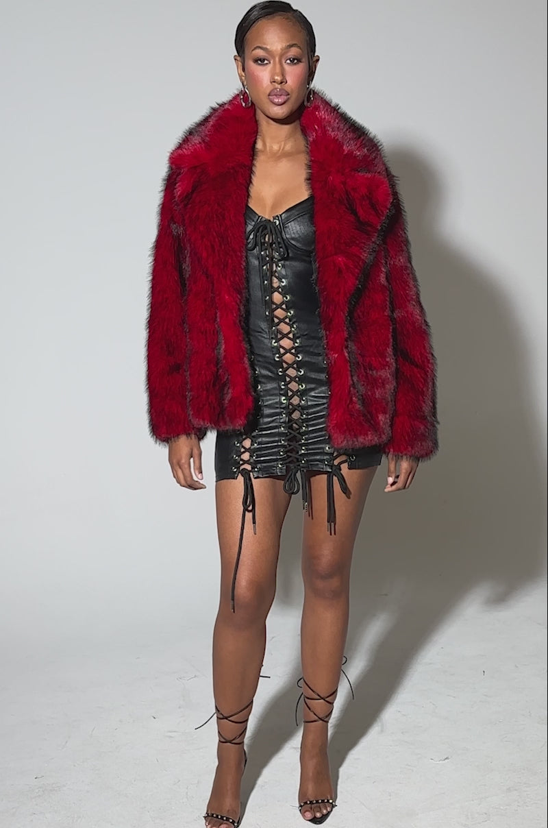 Video of woman modeling the NO LOOKING BACK FAUX FUR IN RED MULTI, an oversized jacket with bold red and black accents