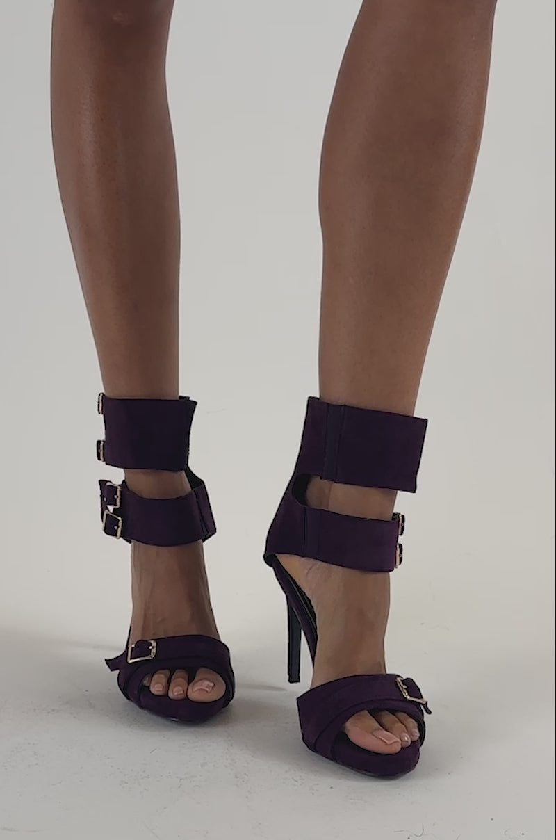 Video of a woman modeling the AZALEA WANG TARA EGGPLANT BUCKLE STILETTO SANDAL, striking purple suede evening sandals with multiple straps and buckles.