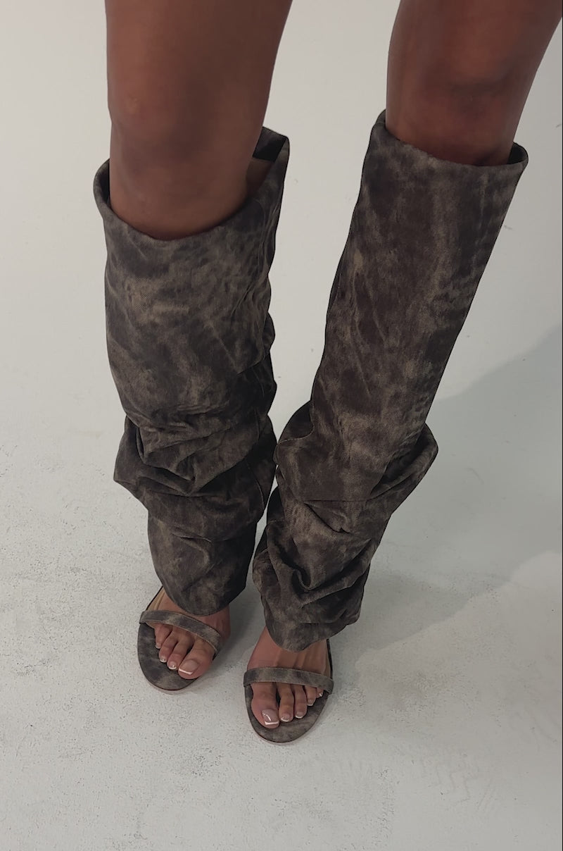 Video of woman modeling the AZALEA WANG BROWN ACID WASHED DENIM GLADIATOR SANDAL with oversized, tie-dye brown leg covers against a plain, light-colored background.