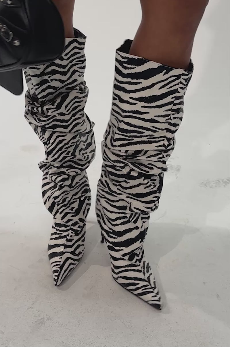 Video of a woman modeling the AZALEA WANG STERRE BLACK AND WHITE ZEBRA PRINT STILETTO BOOT, which features a bold black-and-white striped pattern and slouchy knee-high design.