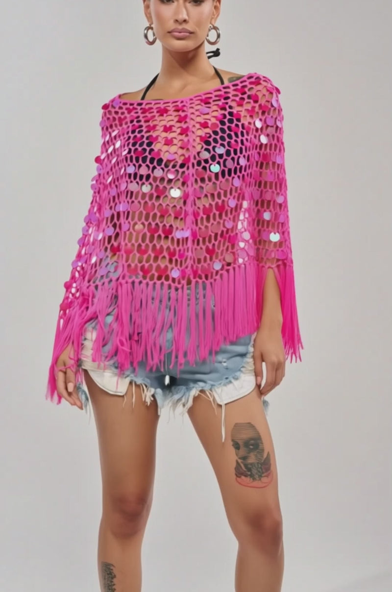 Video of woman modeling the ITS MY WORLD CROCHET SEQUIN PONCHO in hot pink over a bikini top and denim shorts, standing against a plain light background.