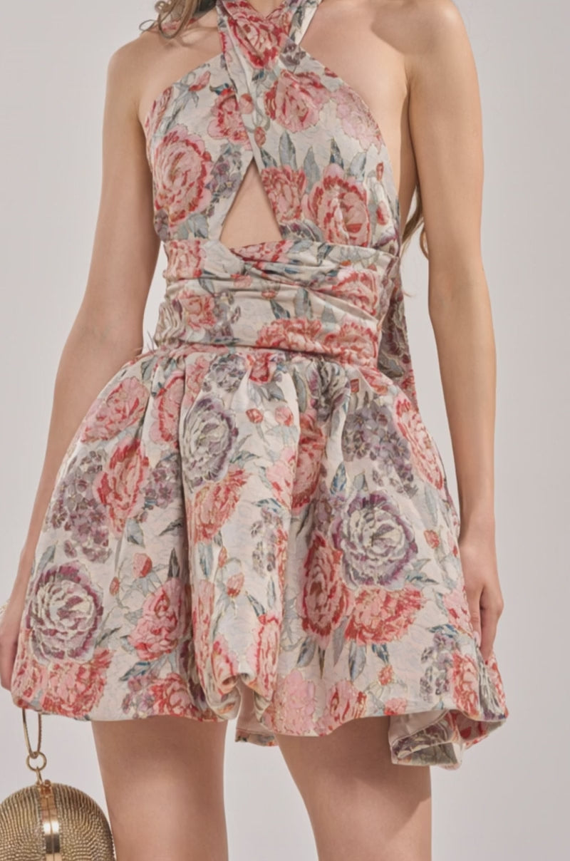 Video of woman modeling the PRINT OF THE SEASON BUBBLE MINI DRESS IN BROCADE—sleeveless, halter-neck, and floral with a keyhole neckline. 