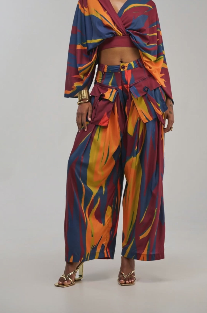 Video of a woman modeling the TAKE ME AWAY TROUSER, featuring a colorful abstract multicolor print and high-rise wide-leg silhouette.