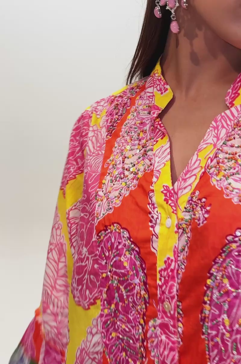 A video of a woman wearing the DANCING TILL SUNRISE FLORAL LONG SLEEVE DRESS, a colorful mini dress featuring vibrant pink, orange, yellow, green, and purple patterns.