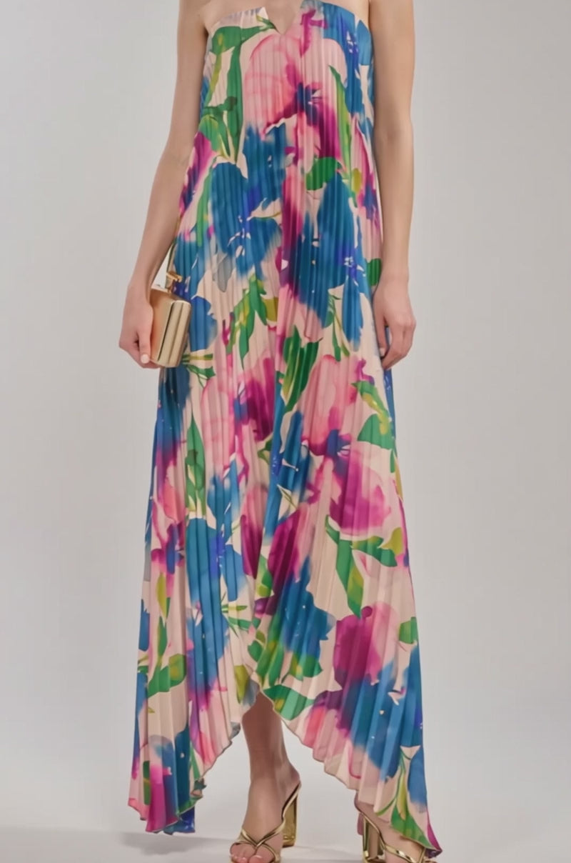 Video of woman modeling the COCKTAIL HOUR FLORAL STRAPLESS MAXI DRESS in a blue, pink, and green floral print, paired with a beige clutch, gold heeled sandals, and hoop earrings