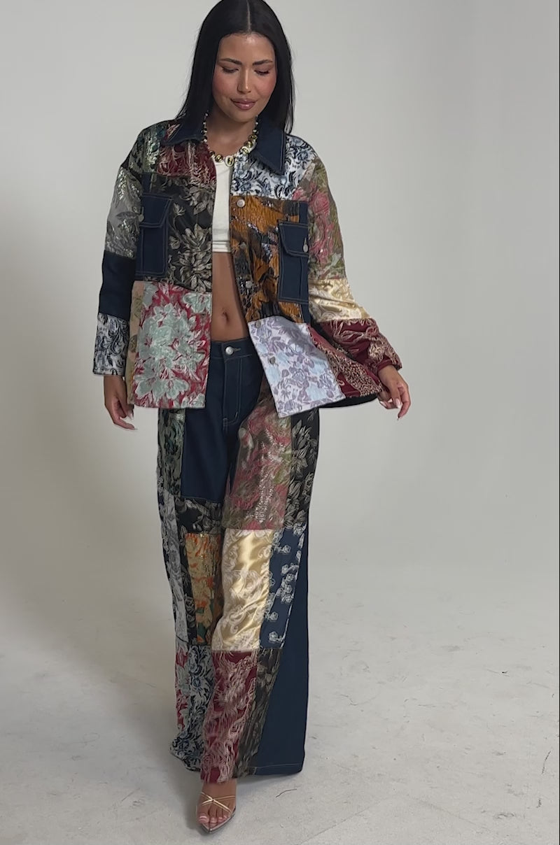Video of woman modeling the EMOTIONLESS BUTTON DOWN, a loose-fitting denim shirt paired with colorful floral patchwork pants