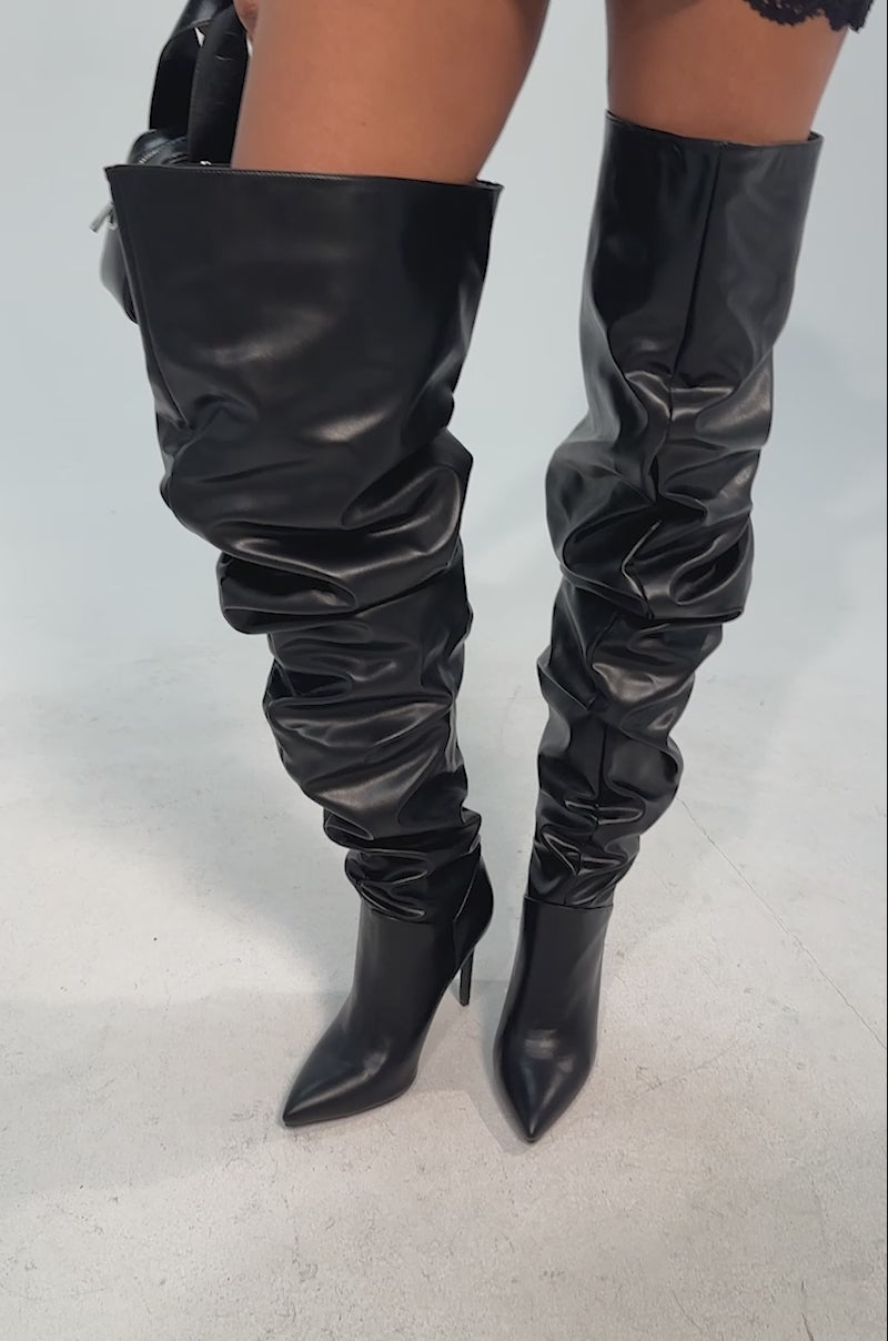 Video of woman modeling the AZALEA WANG TORVIS RUCHED STILETTO BOOT IN BLACK and carrying a small black handbag with silver buckles. 