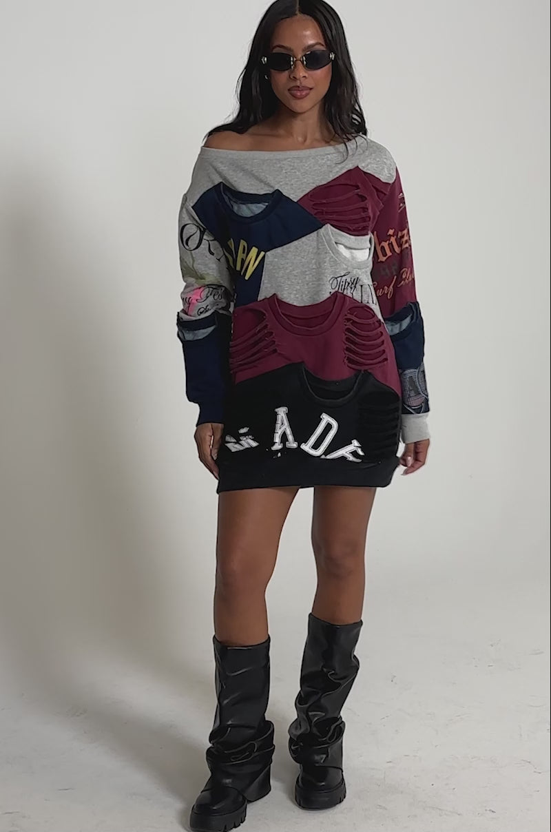 Video of woman modeling the TALK LATER OFF THE SHOULDER PATCHWORK DRESS, featuring colorful patchwork, printed text, and cut-out details, styled as an oversized mini dress with sunglasses