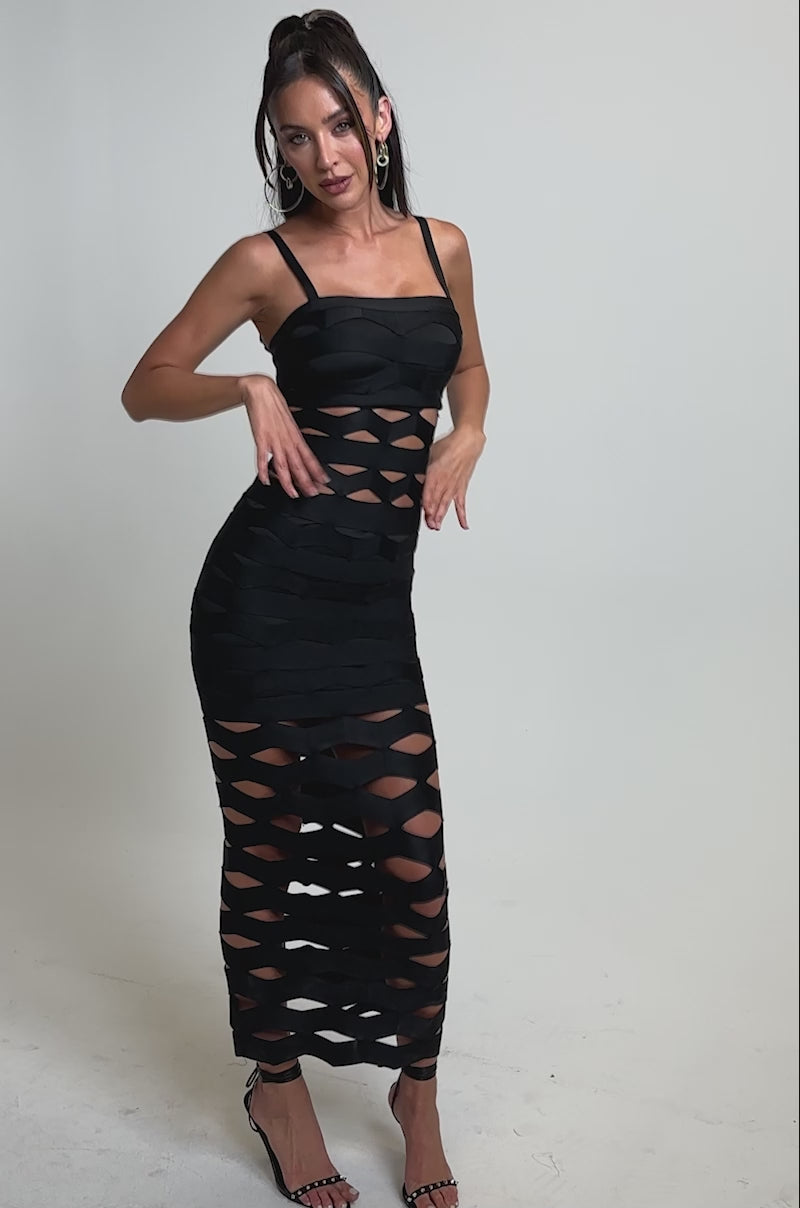 A video of a woman in the STREET CHIC MAXI DRESS, featuring a black geometric cutout design, fitted top, and mermaid silhouette. 
