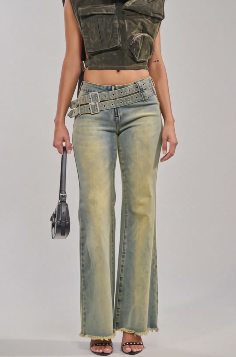Video of woman modeling the MODEL BEHAVIOR TOP IN DARK OLIVE DENIM and light blue jeans adorned with multiple belts and buckles.