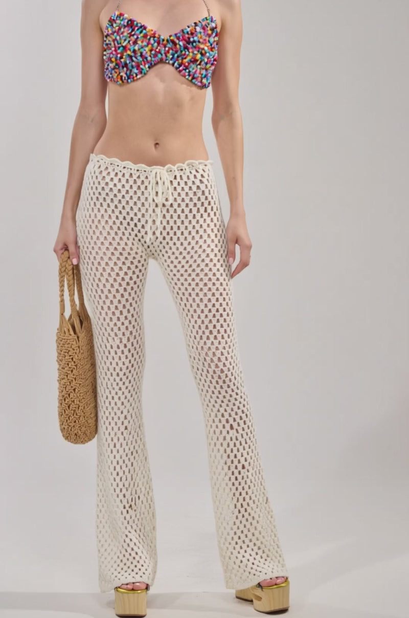 Video of woman modeling the SWEET LIKE CANDY BEADED BRALETTE, and high-waisted white crochet pants