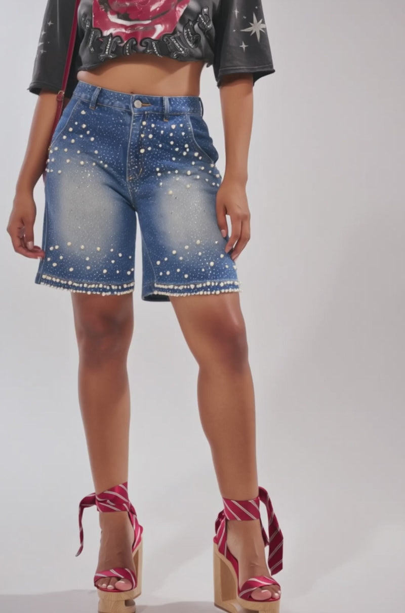 A video of a person wearing BLINGED OUT CARGO SHORTS IN MEDIUM BLUE DENIM with pearl embellishments and red platform sandals with ribbon ankle ties.