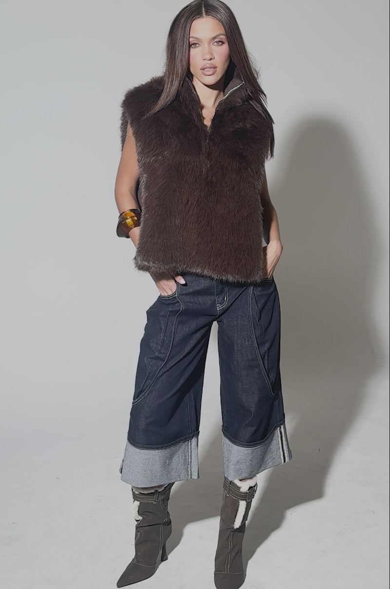 Video of woman modeling the SURE THANG FUR TURTLENECK PULLOVER, paired with dark wide-leg cuffed jeans, brown heeled boots, and a chunky bracelet, her hands tucked stylishly in her pockets.