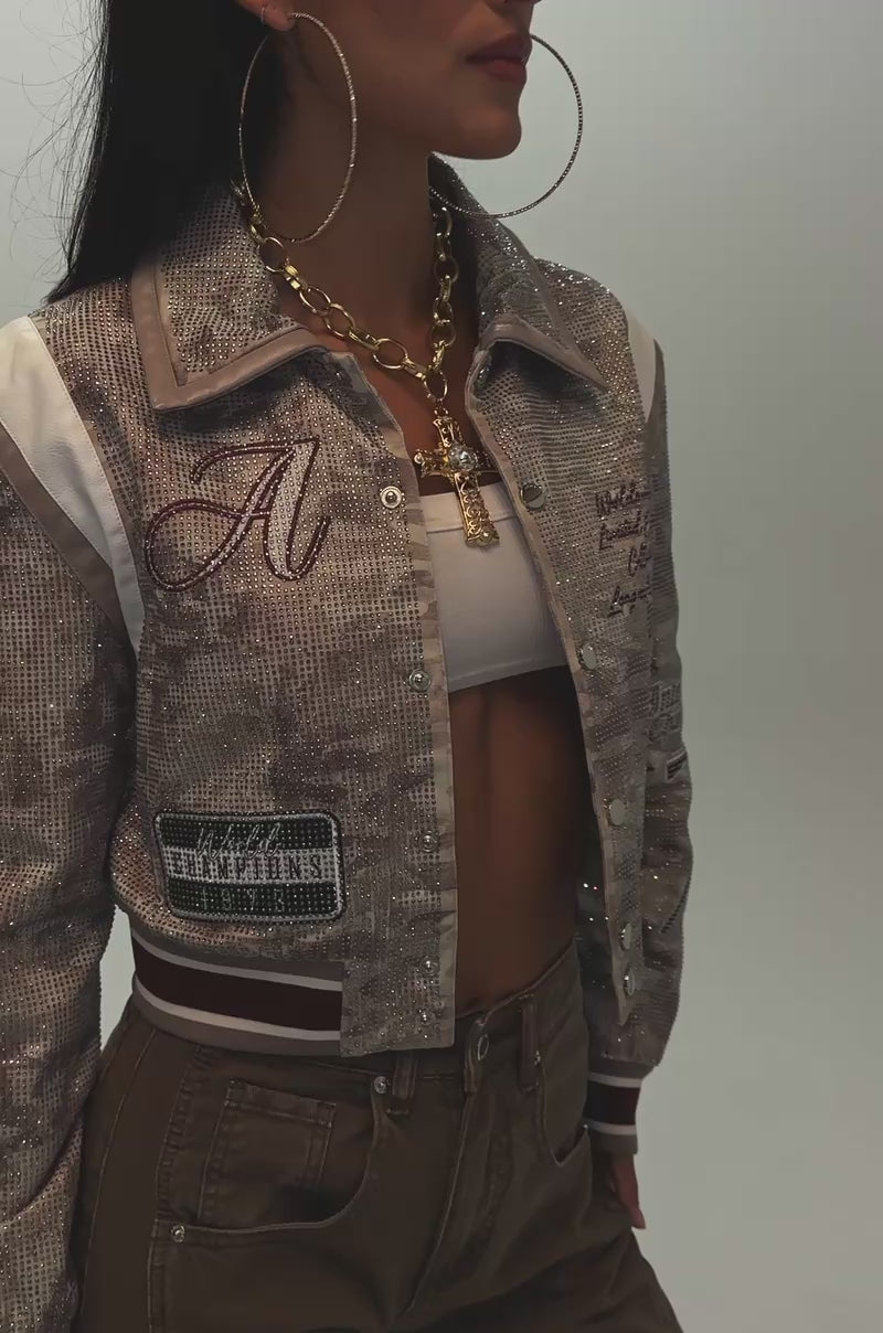 Video of a woman modeling the BIG EGO RHINESTONE BOMBER IN CAMO, featuring bold embellishments and patches.