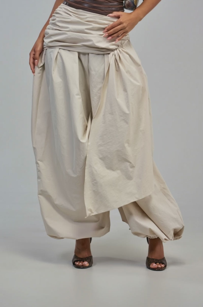 Video of a woman modeling the NOT MY TYPE TROUSER—loose, draped balloon trousers in beige fabric.