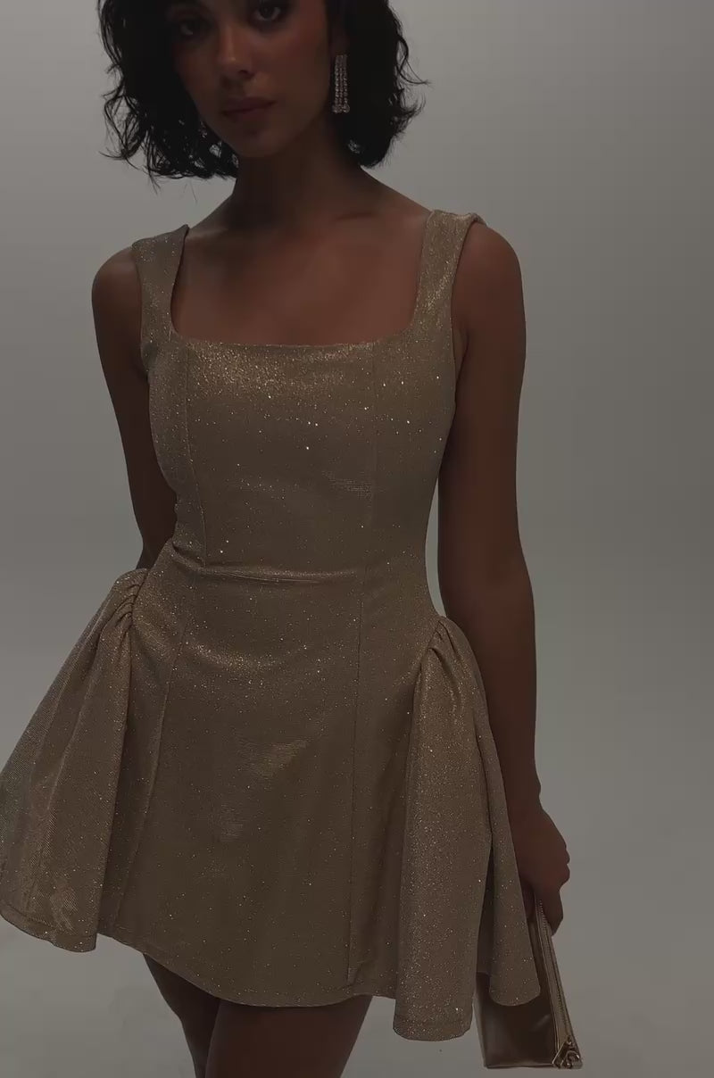 Video of a woman modeling the YOUR PERFECT DATE SPACESHINE MINI DRESS IN GOLD—with its sparkly gold finish, corset-style bodice, and structured side panels.