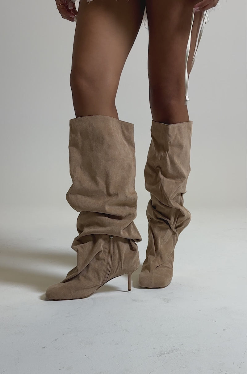 A video of a person against a plain background wearing the AZALEA WANG RANDALL NUDE RUCHED SUEDE BOOT, knee-high stilettos in tan faux suede with a side zipper.