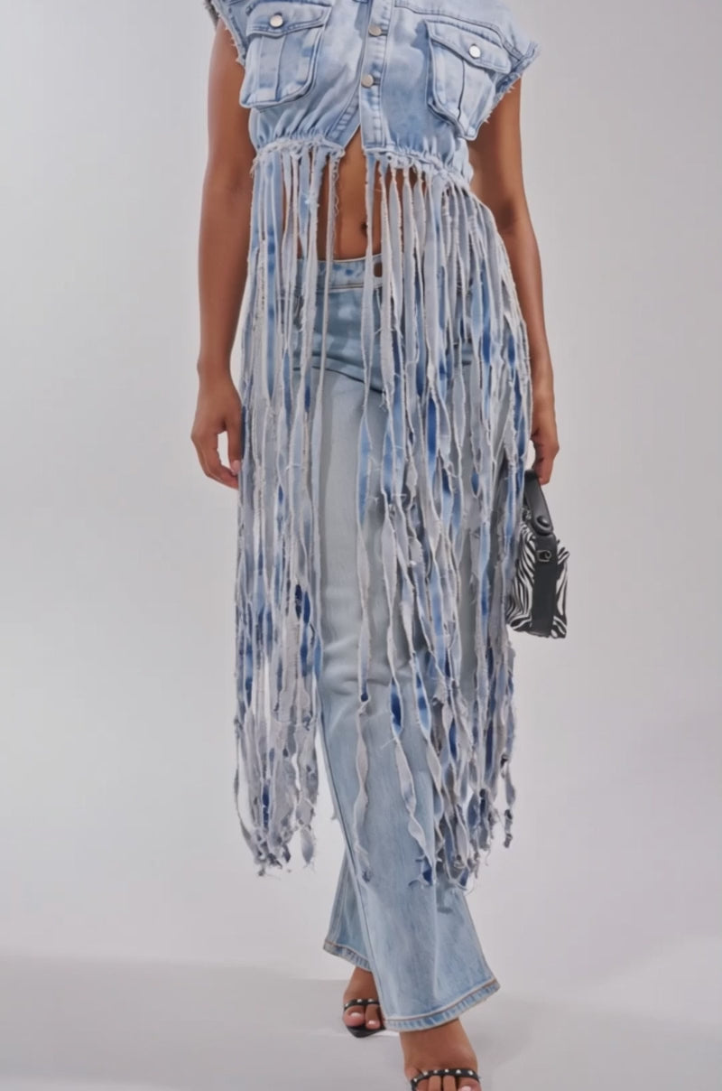 A video of a woman in the ROCK ON DENIM FRINGE TOP in light blue distressed denim with matching jeans, styled for festival streetwear. 