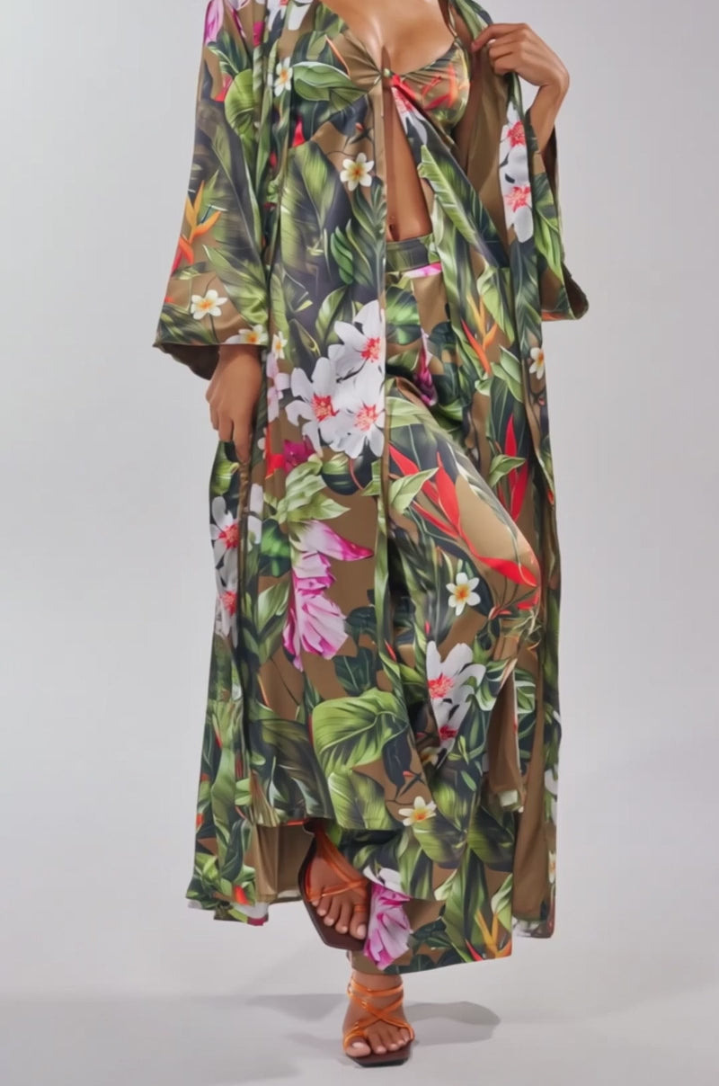 A video of a woman wearing the INTO THE WILD FLORAL DUSTER over a coordinating swimsuit with brown sandals. 