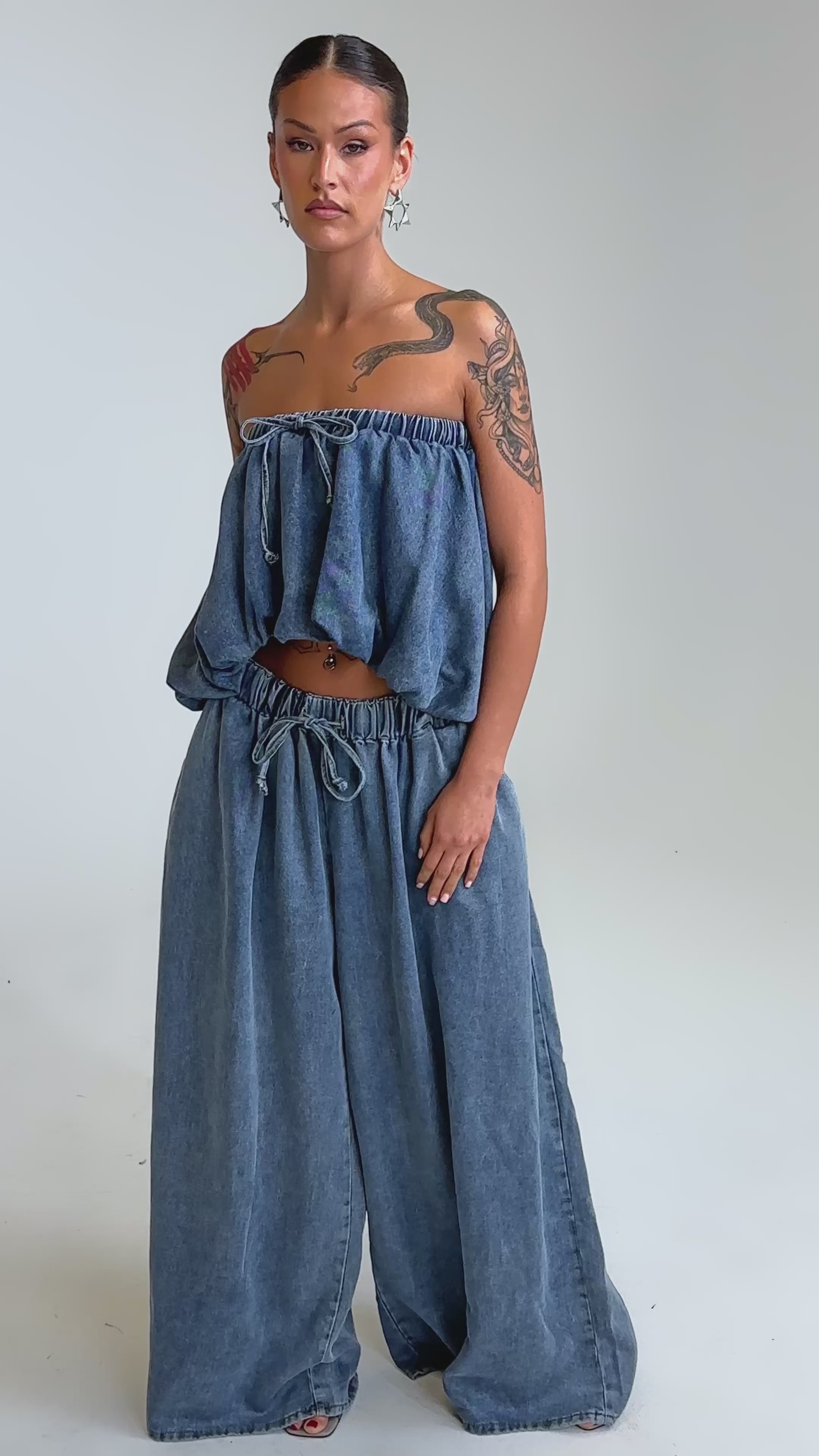 Video of woman modeling the DENIM FOR DAYS JOGGER, a loose-fitting, strapless blue high rise denim top paired with wide leg pants.