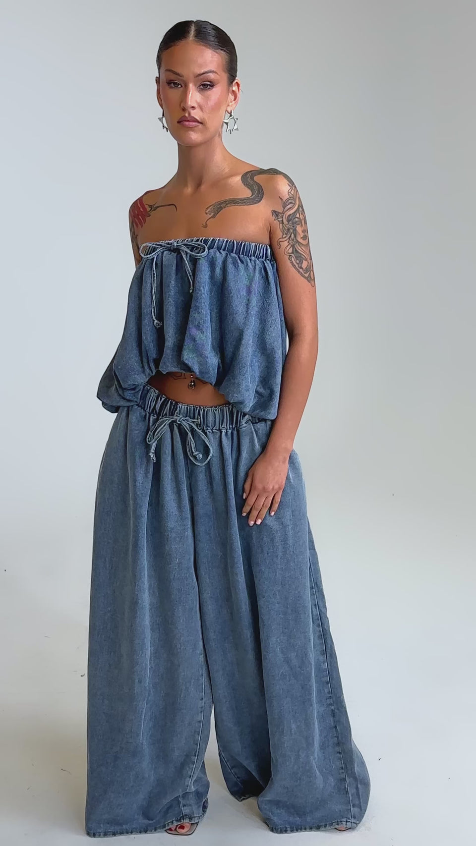 Video of woman modeling the DENIM FOR DAYS JOGGER, a loose-fitting, strapless blue high rise denim top paired with wide leg pants.