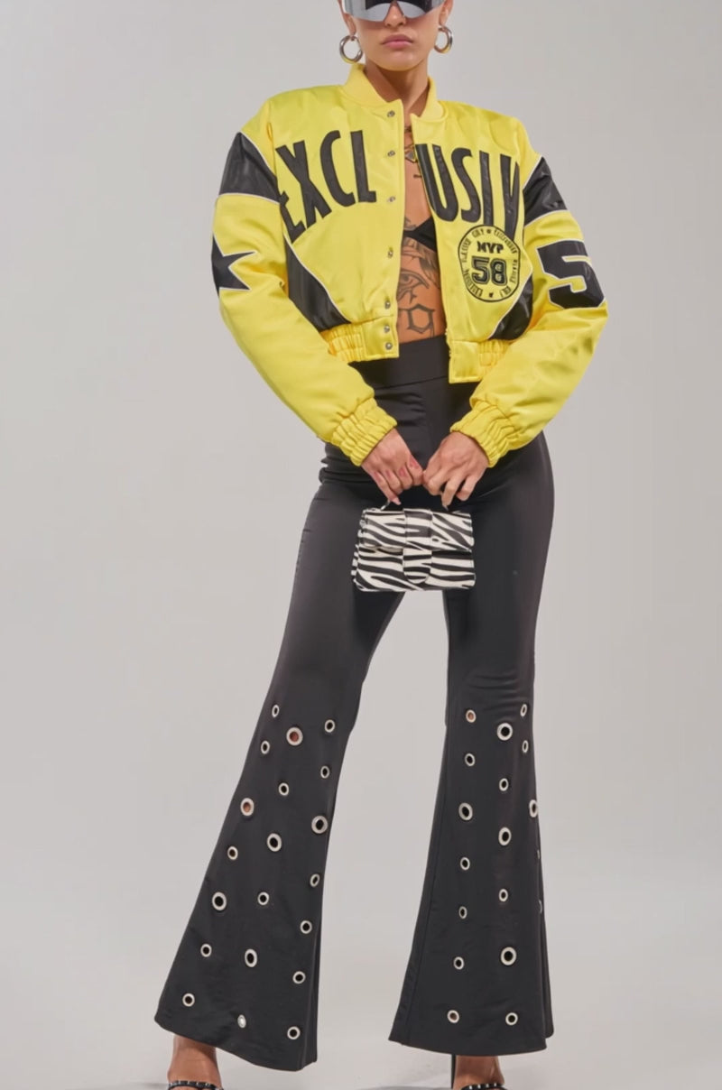 Video of woman modeling the BILLIE EMBROIDERED NYLON BOMBER, styled with large sunglasses, a black top, black leggings, and a small patterned bag.