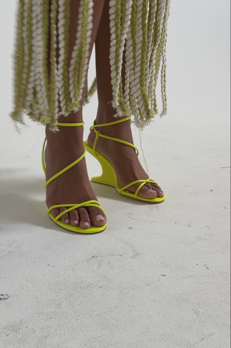 A video of a person wearing a skirt of twisted white and yellow-green rope strands, paired with the AZALEA WANG VINTARA YELLOW NOVELTY WEDGE STRAP SANDAL.