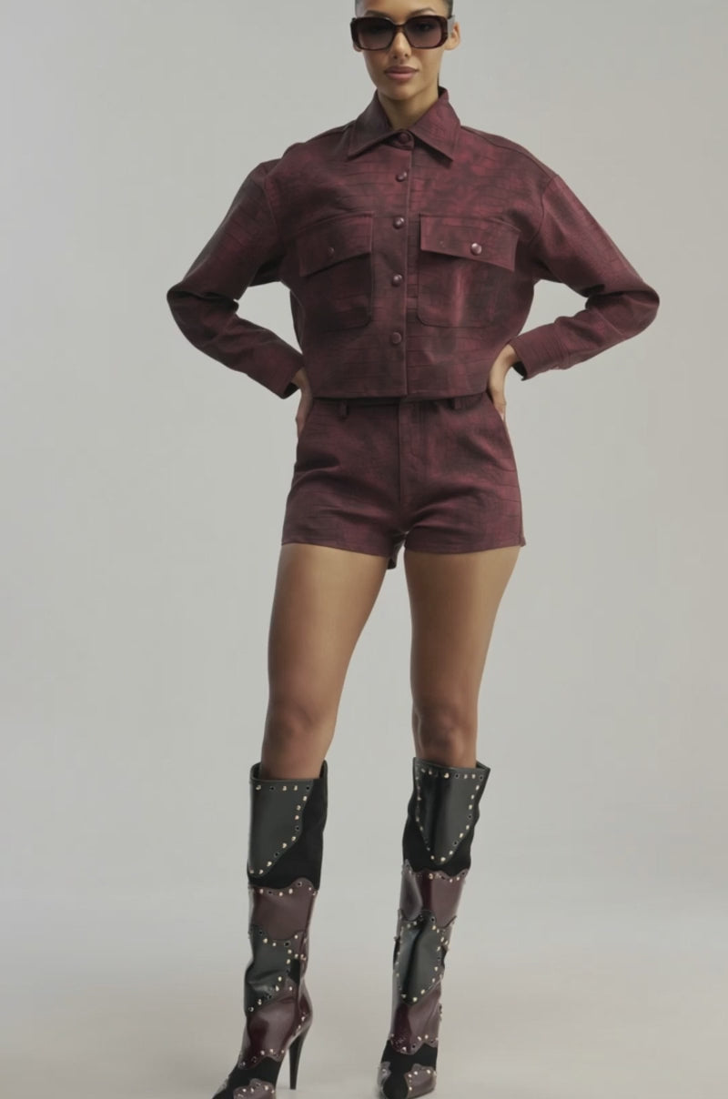 Video of a woman modeling the MOODY CROC LONG SLEEVE BLOUSE, a textured burgundy crocodile-patterned button-down jacket with large buttons.