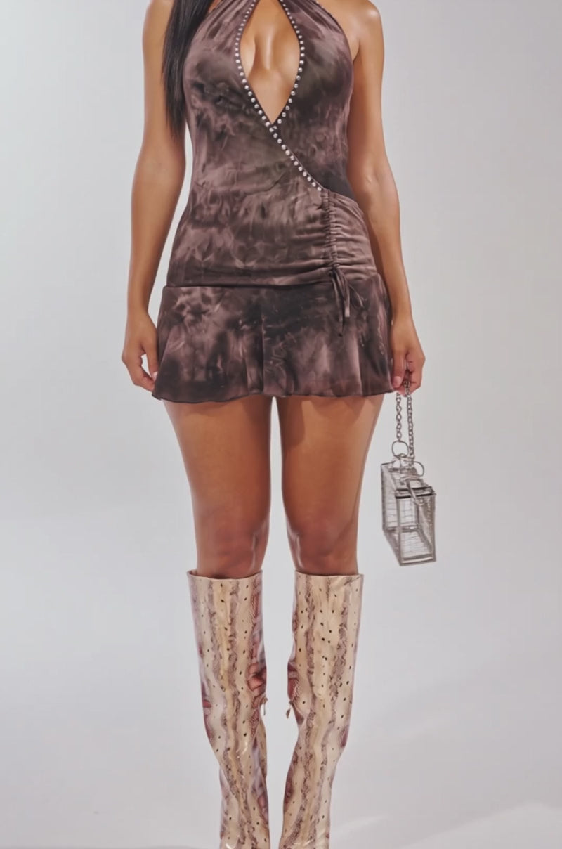 Video of woman modeling the GROOVE AND MOVE PRINTED MINI DRESS featuring brown tie-dye, a deep V-neckline, and studded trim. 