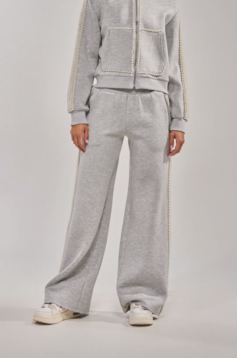 Video of woman modeling the PEARL GIRL WIDE LEG JOGGER IN GREY, paired with a light gray zip-up jacket and white sneakers against a plain light background.